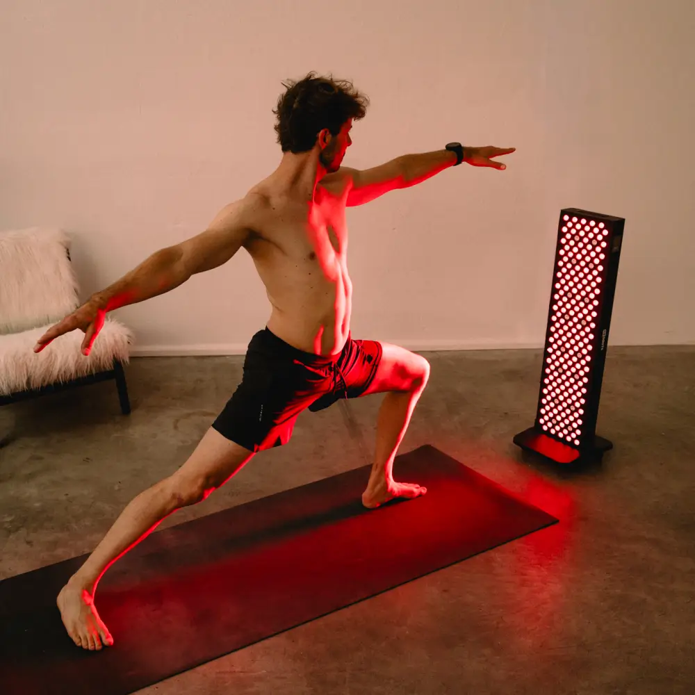 Ein Athlet hält die Krieger-Yoga-Position auf einer Trainingsmatte im roten Lichtstrahl des Reboots Relight Pro Panels.