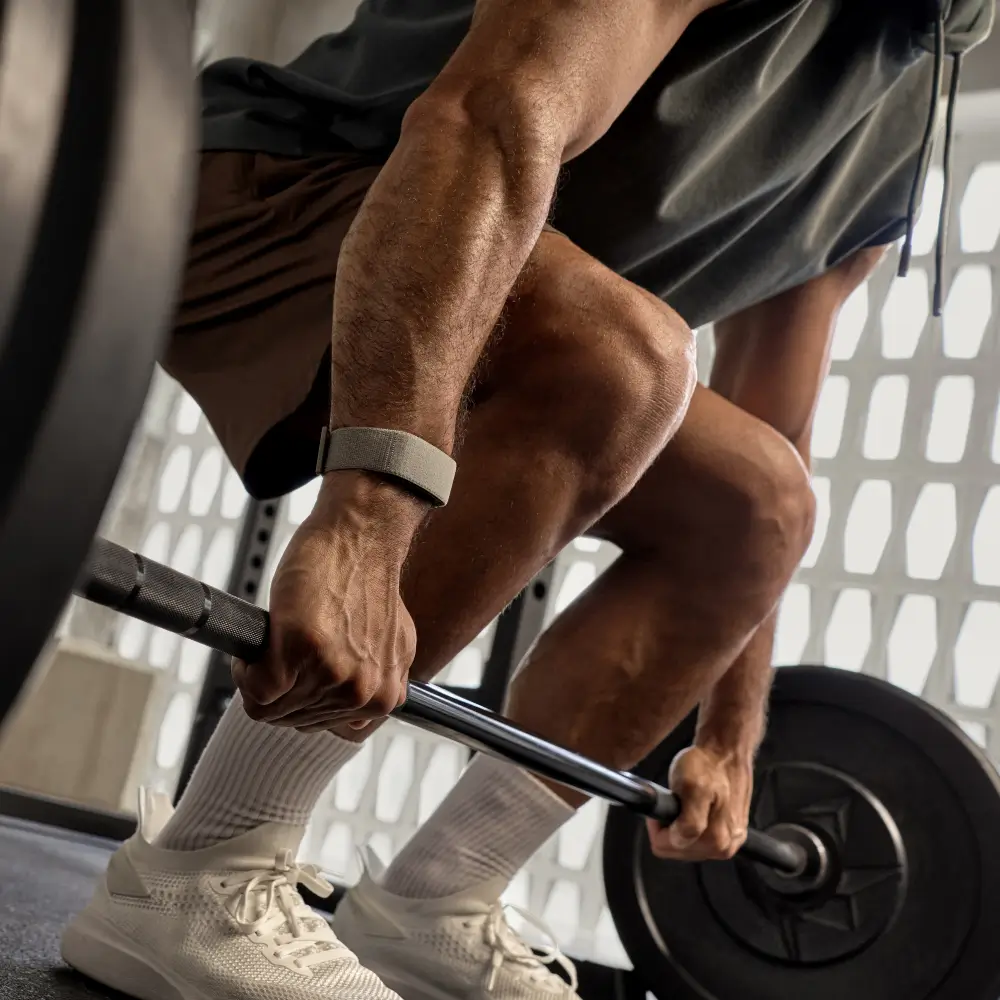 Garmin Cirqa Smart Band in French Gray am Handgelenk eines Sportlers beim Heben einer Langhantel beim Krafttraining