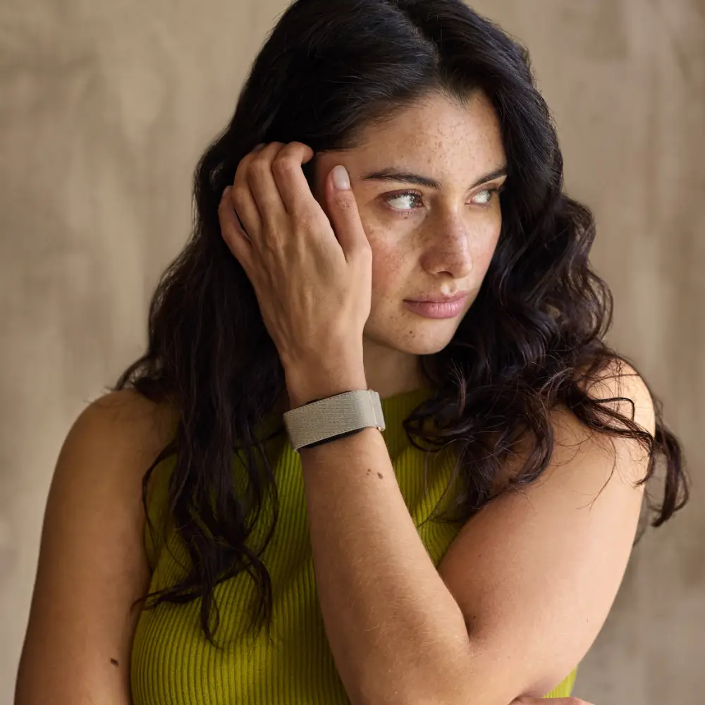 Eine Frau im sportlich-eleganten Lifestyle-Outfit trägt das dezente Garmin Cirqa Smart Band in French Gray als Alltags-Accessoire