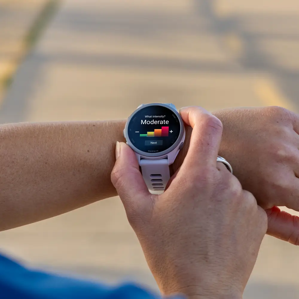 Eine Sportlerin bedient die Abfrage der Trainingsintensität auf dem Touchscreen ihrer steinweißen Garmin Forerunner 170 Music