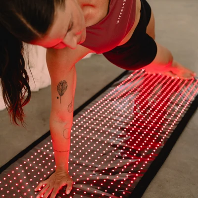 Reboots: Frau macht yoga auf Relight Rotlicht Matte